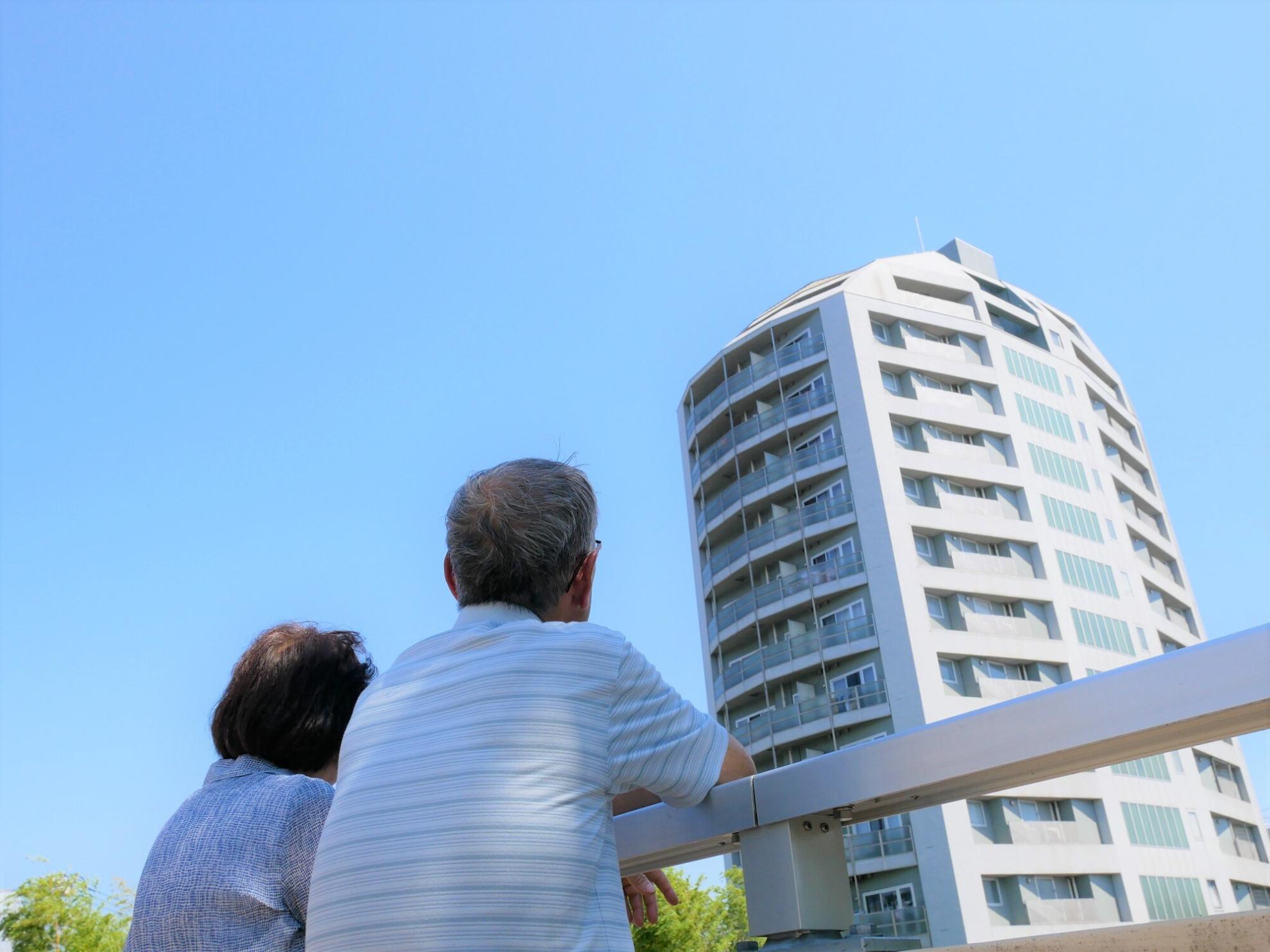 マンションを見上げるシニア夫婦