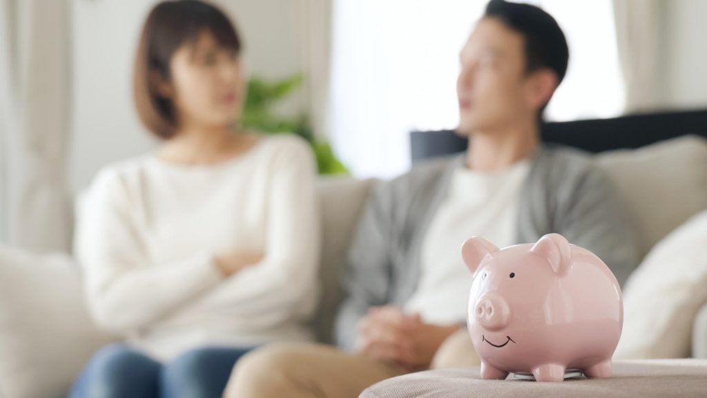 ブタの貯金箱と話し合う夫婦